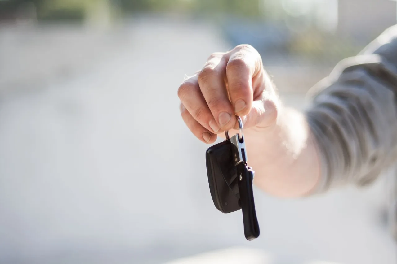 Hand holding out a set of car keys before a rental handover